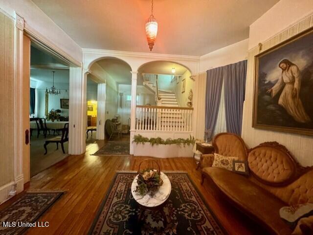 206 Linton Ave, Natchez, MS 39120 - living area featuring decorative columns, wood finished floors, arched walkways, stairway, and a chandelier