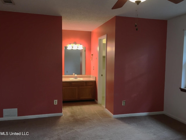 unfurnished bedroom with ceiling fan, sink, light carpet, and connected bathroom