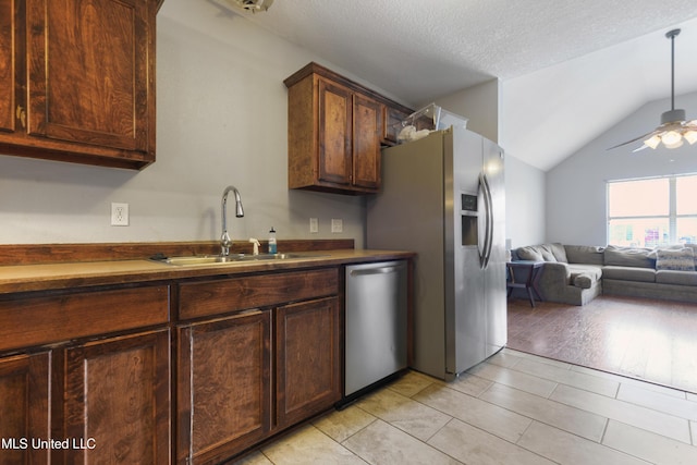 kitchen featuring a ceiling fan, a sink, open floor plan, stainless steel appliances, and vaulted ceiling