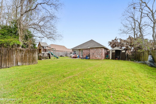 view of yard with a storage shed, a playground, a fenced backyard, and an outdoor structure