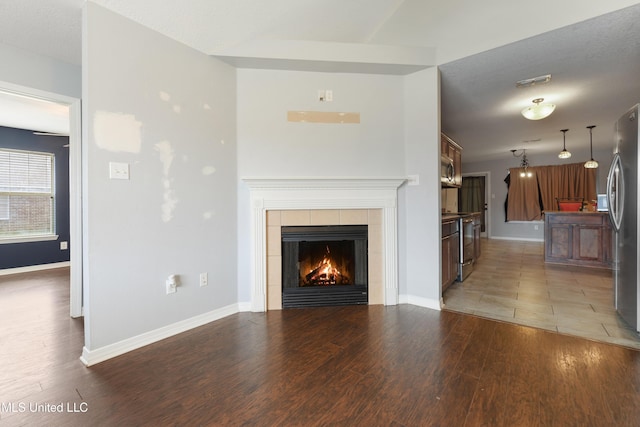 unfurnished living room featuring a fireplace, light wood-style floors, visible vents, and baseboards