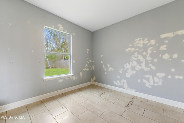 tiled empty room featuring baseboards