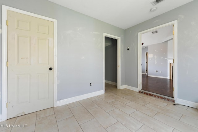 unfurnished bedroom featuring light tile patterned floors, visible vents, and baseboards