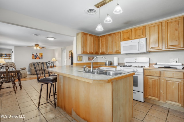 kitchen featuring kitchen peninsula, sink, white appliances, and light tile patterned floors