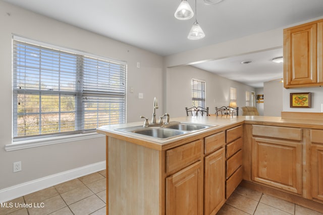 kitchen with kitchen peninsula, sink, decorative light fixtures, and light tile patterned floors