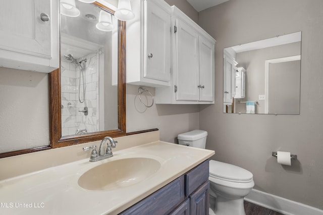 bathroom with a tile shower, vanity, hardwood / wood-style flooring, and toilet