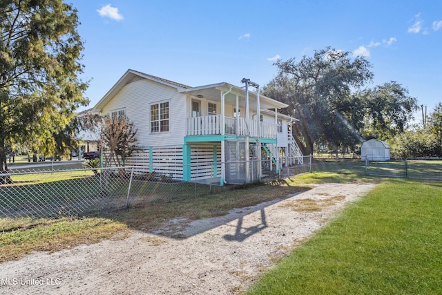 view of front of home with a porch, a front yard, and a shed