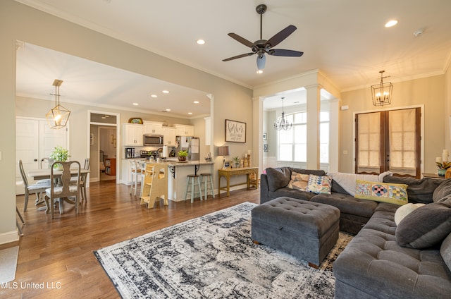 living room featuring crown molding, hardwood / wood-style floors, and ceiling fan with notable chandelier