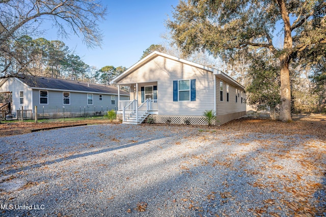 view of front facade featuring a porch, driveway, and fence