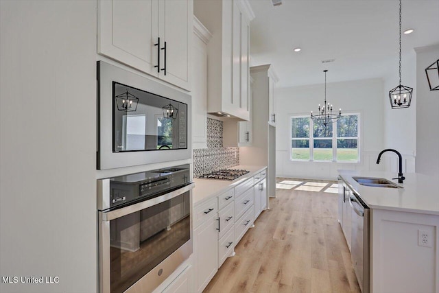 1025 Mullican Rd, Florence, MS 39073 - kitchen featuring appliances with stainless steel finishes, a sink, light countertops, a notable chandelier, and light wood-style floors