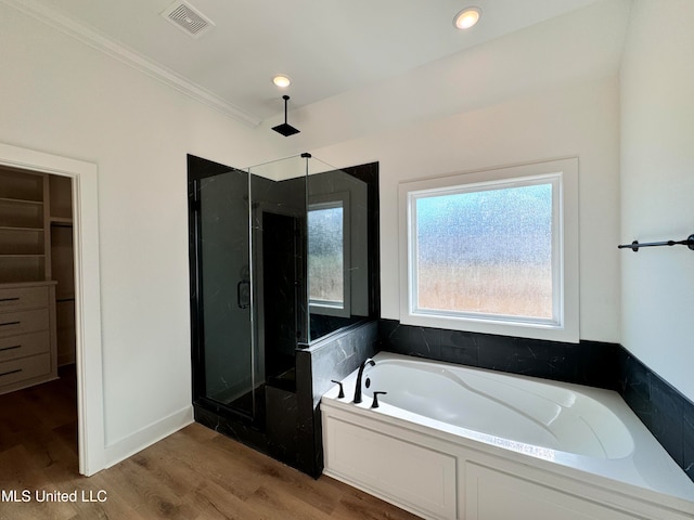 bathroom featuring crown molding, hardwood / wood-style flooring, and shower with separate bathtub