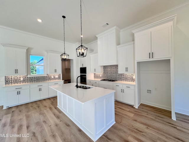 kitchen with white cabinetry, light hardwood / wood-style floors, sink, and a center island with sink