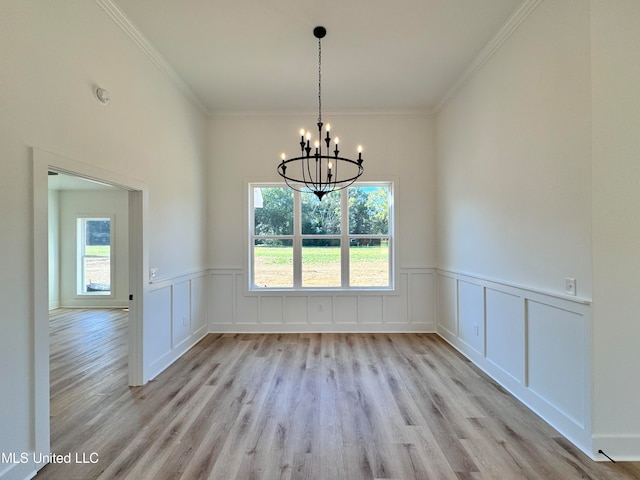 unfurnished dining area featuring ornamental molding, a chandelier, and light hardwood / wood-style flooring