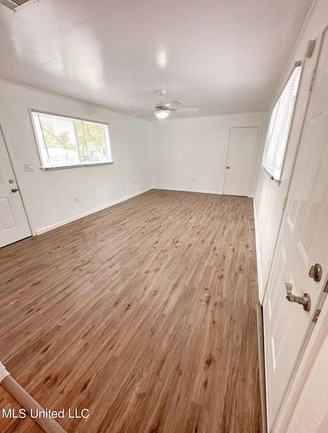 empty room featuring a skylight, light wood-type flooring, and ceiling fan