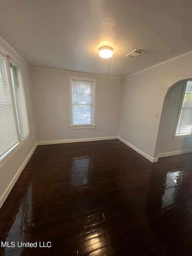 empty room with ornamental molding, dark wood-type flooring, a textured ceiling, and a healthy amount of sunlight