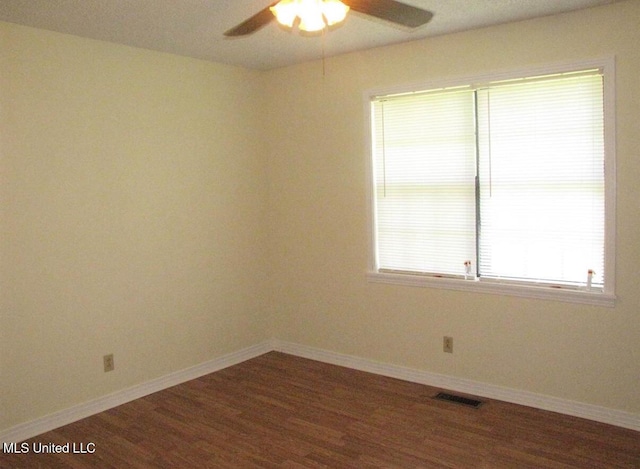 spare room with ceiling fan, dark wood-style flooring, and baseboards