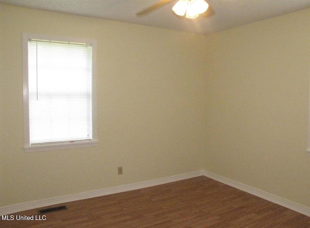 spare room with dark wood-style flooring, plenty of natural light, baseboards, and ceiling fan