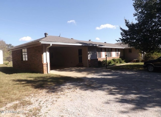 view of front of property with gravel driveway, a carport, and brick siding