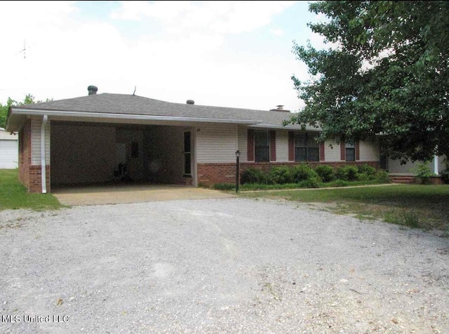 ranch-style house featuring gravel driveway and brick siding
