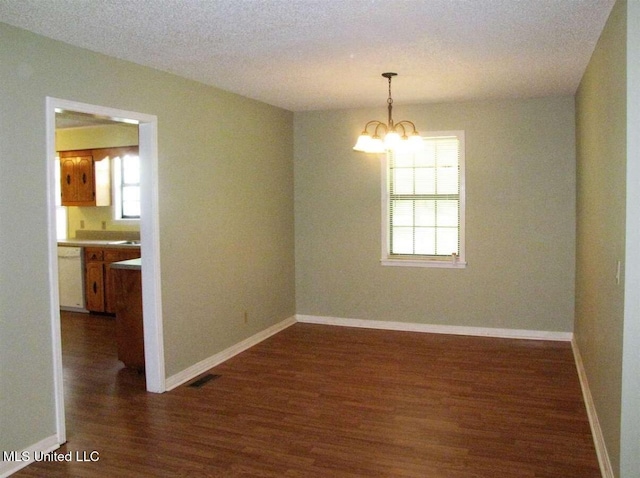 unfurnished room featuring dark wood-style floors, a chandelier, baseboards, and a textured ceiling