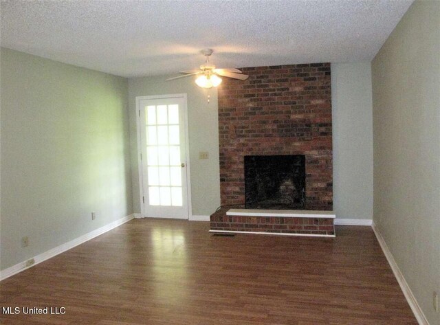 unfurnished living room featuring a ceiling fan, wood finished floors, a fireplace, a textured ceiling, and baseboards