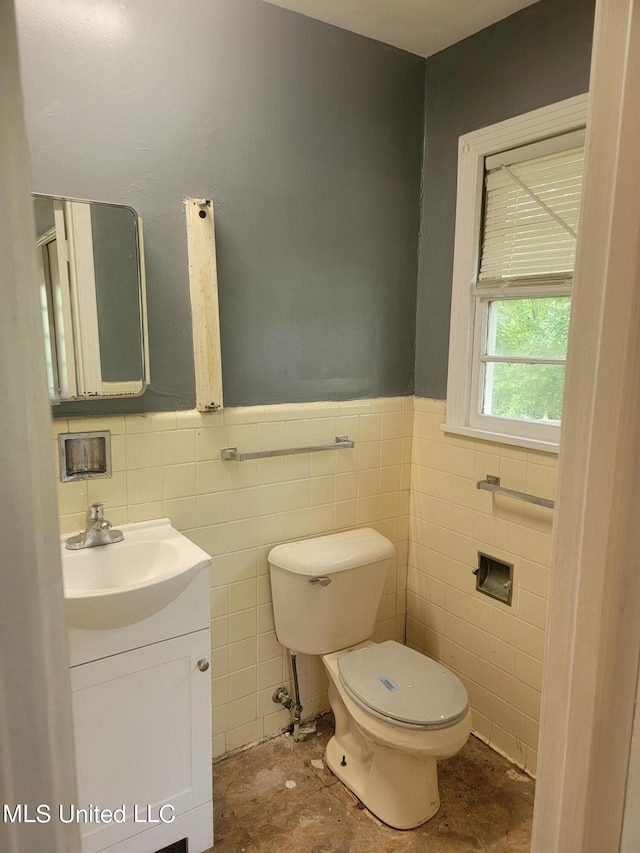 bathroom with vanity, toilet, and tile walls