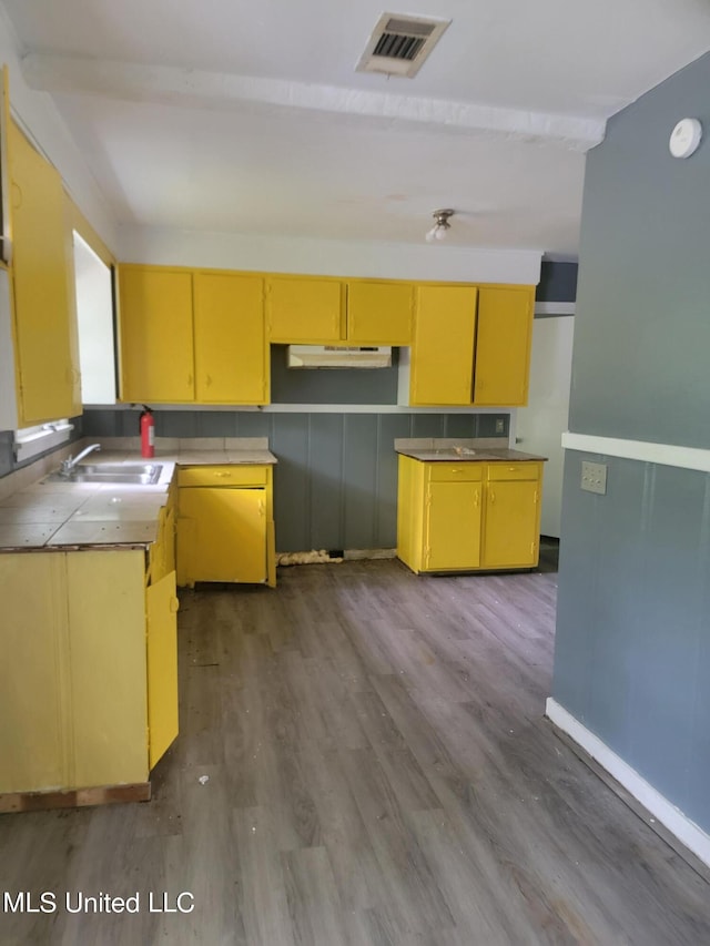 kitchen with beam ceiling, sink, and hardwood / wood-style flooring