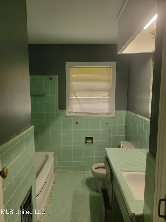 bathroom featuring vanity, toilet, a bathing tub, and tile walls