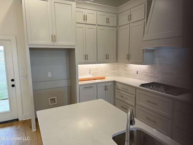 303 Birch Ct Lot 32, Canton, MS 39046 - kitchen with tasteful backsplash, wood finished floors, stainless steel gas stovetop, custom range hood, and light countertops