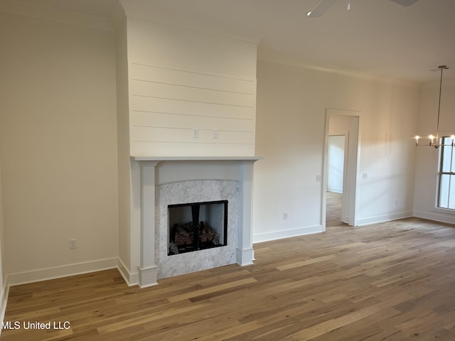 303 Birch Ct Lot 32, Canton, MS 39046 - unfurnished living room with a premium fireplace, crown molding, baseboards, wood finished floors, and ceiling fan with notable chandelier