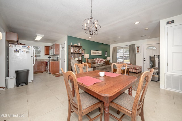 dining space with light tile patterned flooring, a chandelier, and a textured ceiling