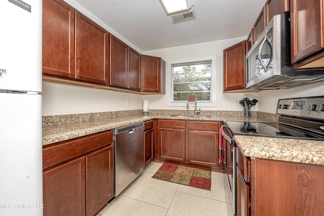 kitchen featuring appliances with stainless steel finishes, sink, light tile patterned floors, and light stone counters