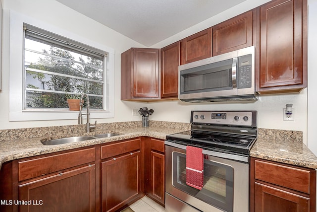 kitchen with appliances with stainless steel finishes, sink, light tile patterned floors, and light stone counters