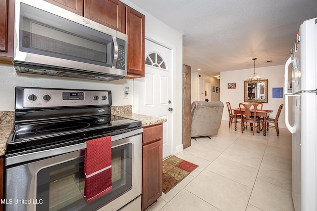 kitchen with stainless steel appliances, decorative light fixtures, light stone countertops, and light tile patterned floors