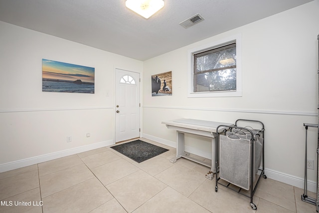 entryway featuring a healthy amount of sunlight, light tile patterned floors, and a textured ceiling