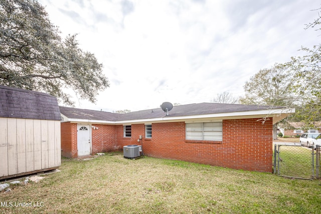 back of house featuring central AC unit, a yard, and a storage shed