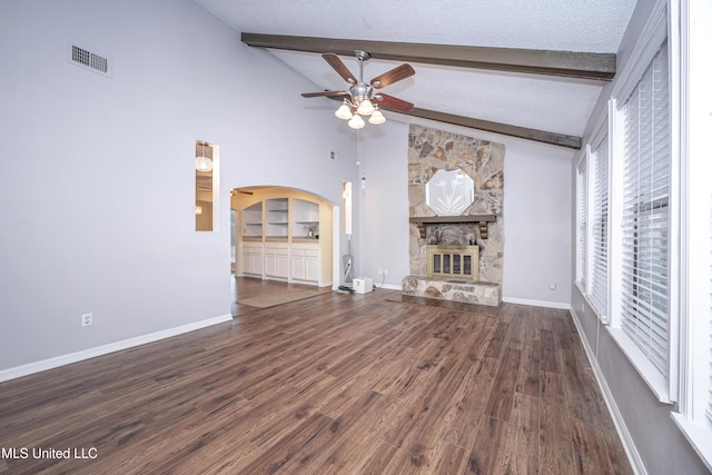 unfurnished living room with arched walkways, a textured ceiling, vaulted ceiling with beams, a fireplace, and visible vents