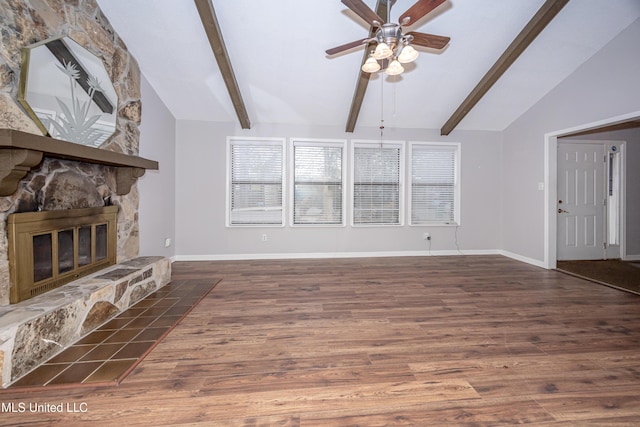 unfurnished living room with vaulted ceiling with beams, a stone fireplace, dark wood finished floors, and baseboards