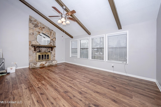 unfurnished living room with baseboards, beamed ceiling, wood finished floors, and a stone fireplace