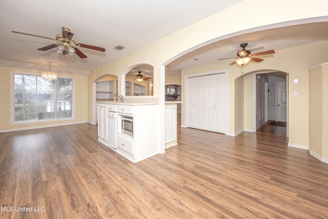 kitchen featuring open floor plan, light countertops, stainless steel microwave, and white cabinetry