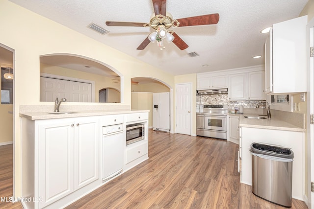 kitchen featuring under cabinet range hood, a sink, white cabinets, light countertops, and appliances with stainless steel finishes