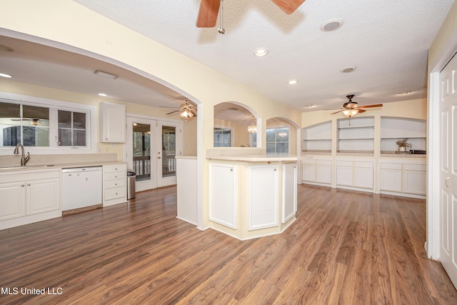 kitchen with light countertops, white dishwasher, a sink, and white cabinets