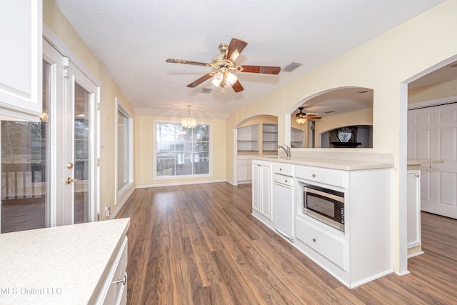 kitchen with visible vents, white cabinets, light countertops, hanging light fixtures, and stainless steel microwave