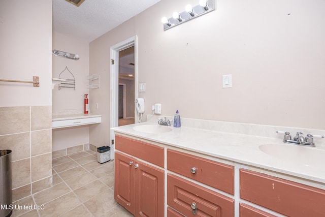 full bathroom with a textured ceiling, double vanity, a sink, and tile patterned floors