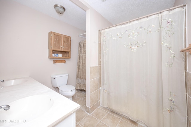 bathroom with double vanity, tile patterned flooring, a textured ceiling, and a sink