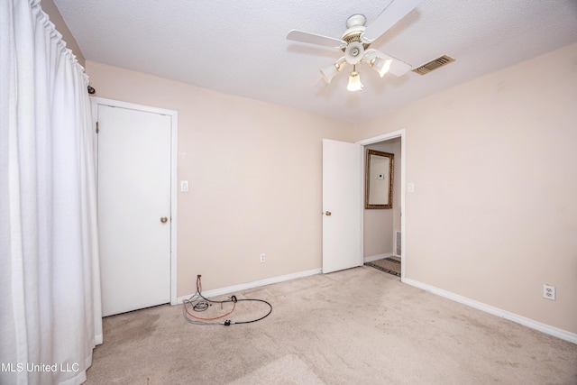 empty room featuring light carpet, baseboards, visible vents, a ceiling fan, and a textured ceiling