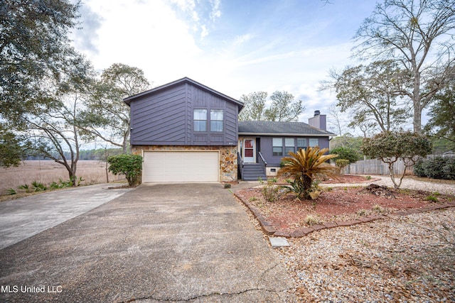 tri-level home with driveway, a chimney, and an attached garage