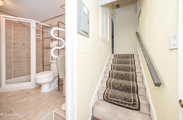 staircase with baseboards, visible vents, a textured ceiling, and tile patterned floors