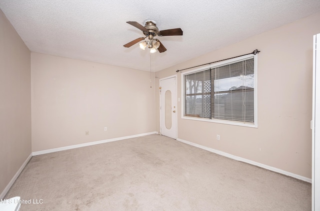 spare room with a textured ceiling, ceiling fan, baseboards, and light colored carpet