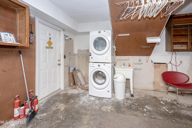 clothes washing area with stacked washer and clothes dryer and laundry area